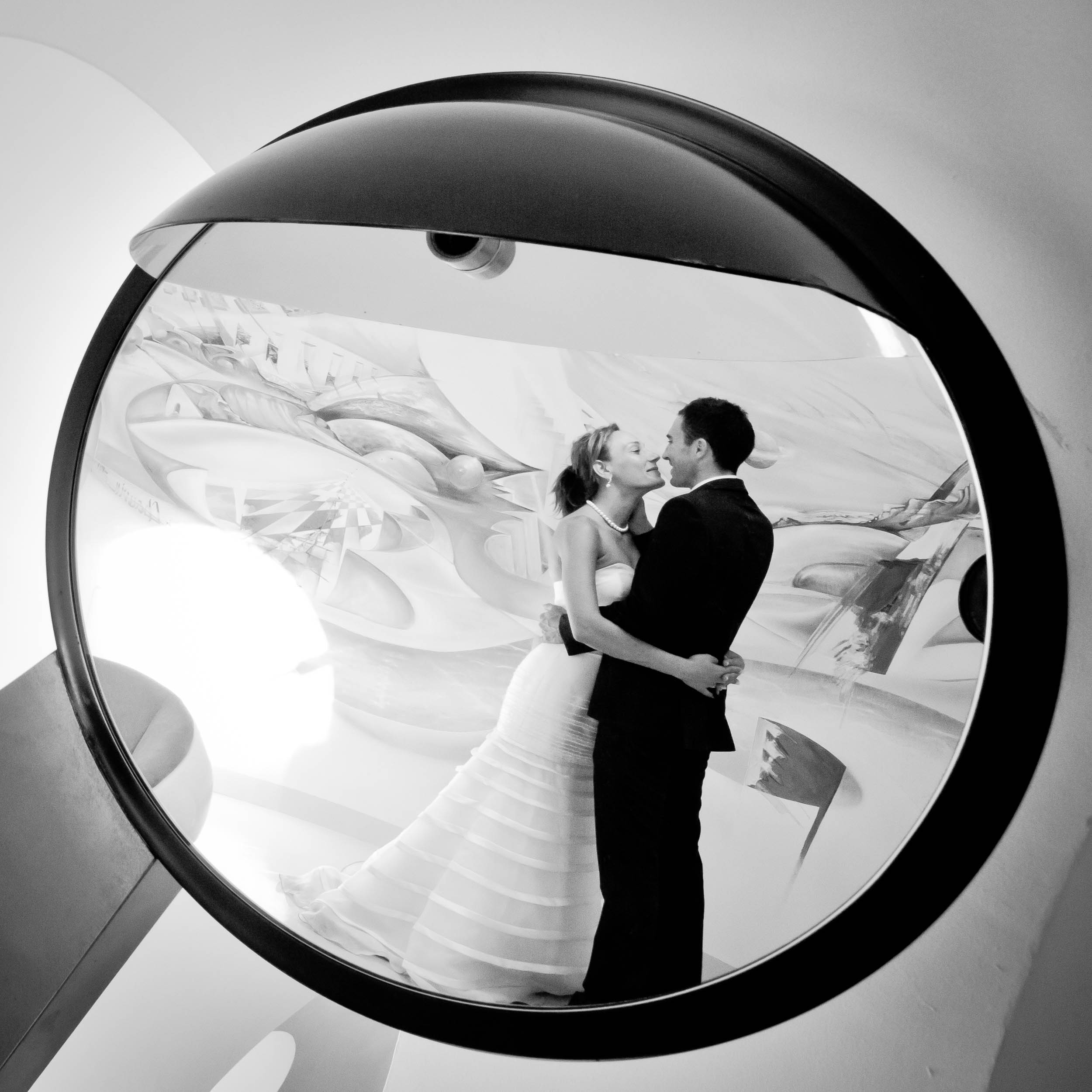 Photo noir et blanc de la mariée appuyée sur le marié alors qu'ils se tiennent la main.