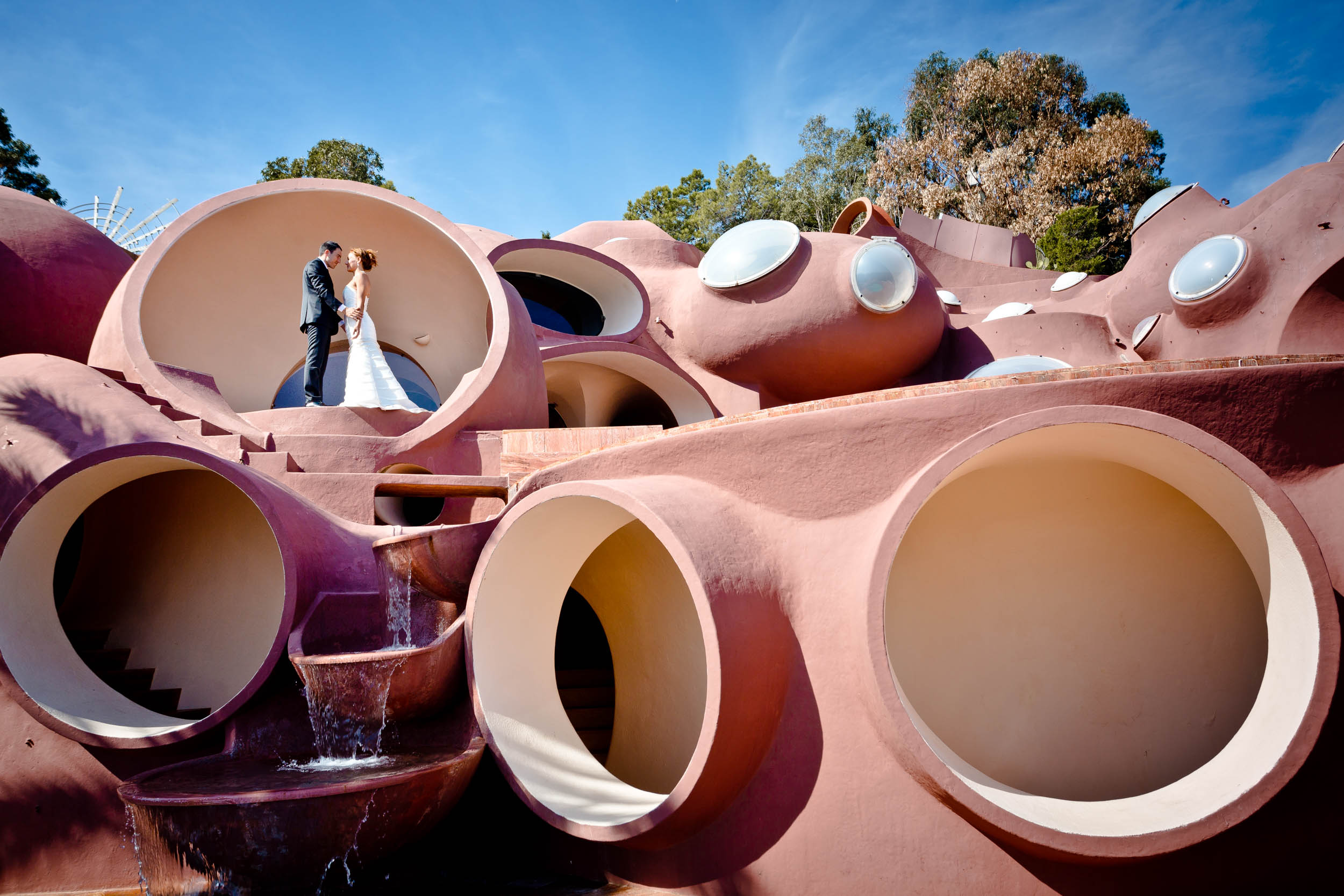 couple en tenue de mariage devant l'une des fenêtres circulaires du Palais Bulles à Cannes.
