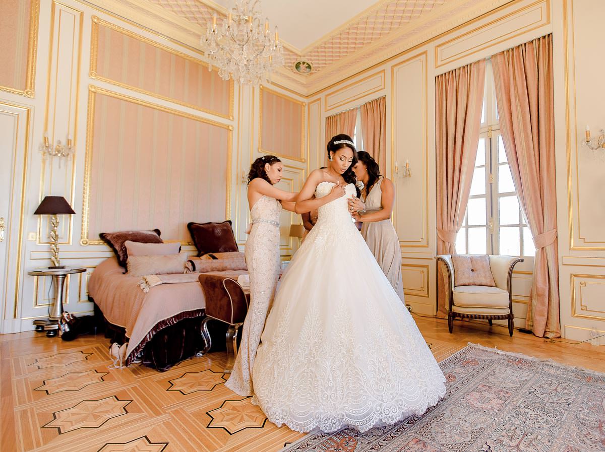 PhotographedemariageaNice - LAWRENCE BANAHAN Wedding Photo côte d'Azur Photographe de mariage à Nice, la mariée entrain d'enfiler sa robe de mariage au chateau